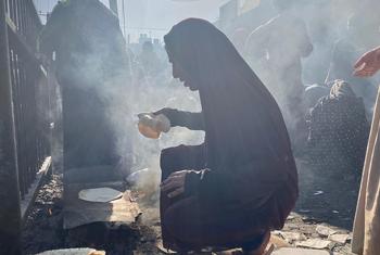 A group of displaced Palestinians gather near a UNRWA shelter in the Nuseirat area of ​​central Gaza, cooking what little food they have.