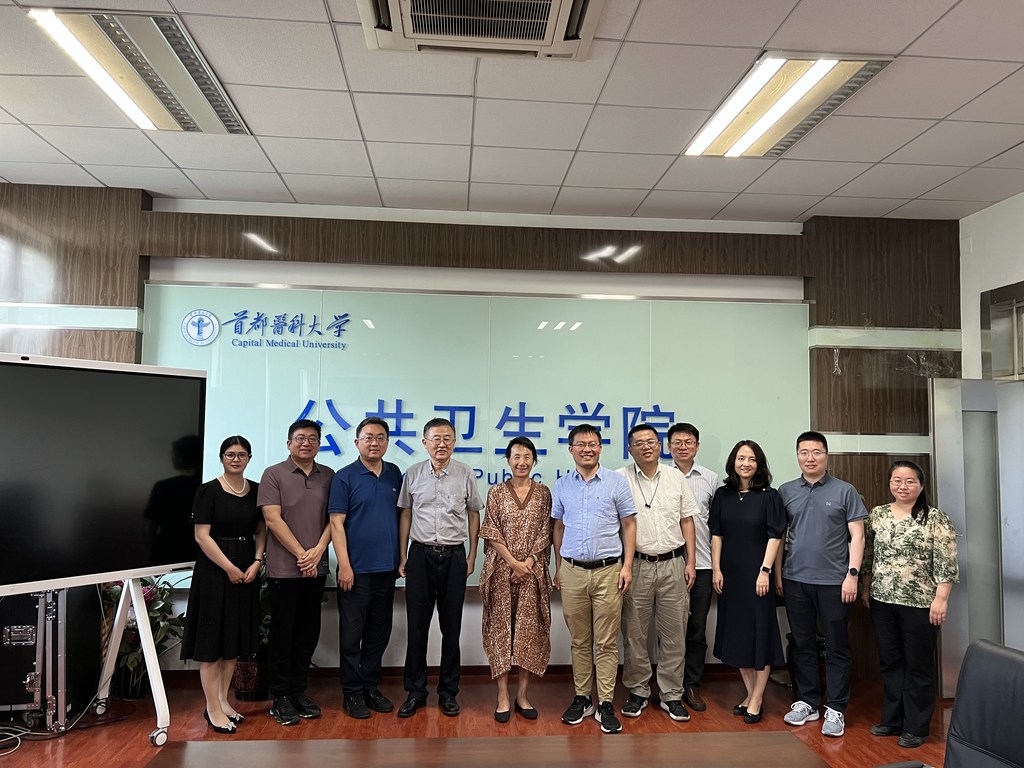 一群人在首都医科大学公共卫生学院的标志牌前合影。