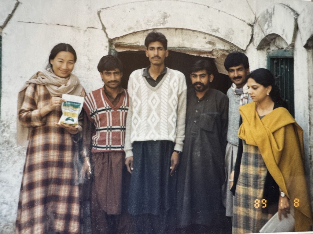 1989年，在巴基斯坦，卢伟和另外五个人站在一栋建筑物前，手里拿着一个包裹。
