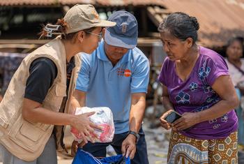 A UNFPA staff member distributes relief supplies to a woman affected by the March earthquakes in Myanmar.