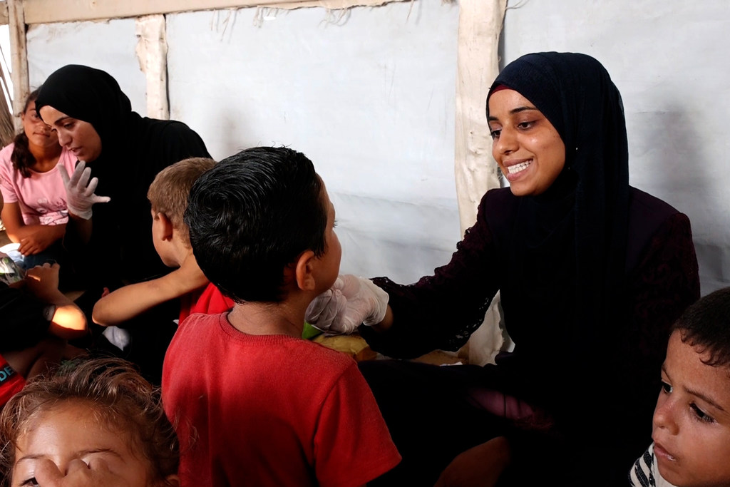 Una logopeda, con hiyab y guantes, atiende a niños palestinos en una clínica de Gaza.