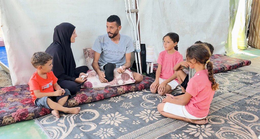 إبراهيم عبد النبي، النازح الفلسطيني في غزة الذي فقد إحدى قدميه، يجلس مع أسرته.