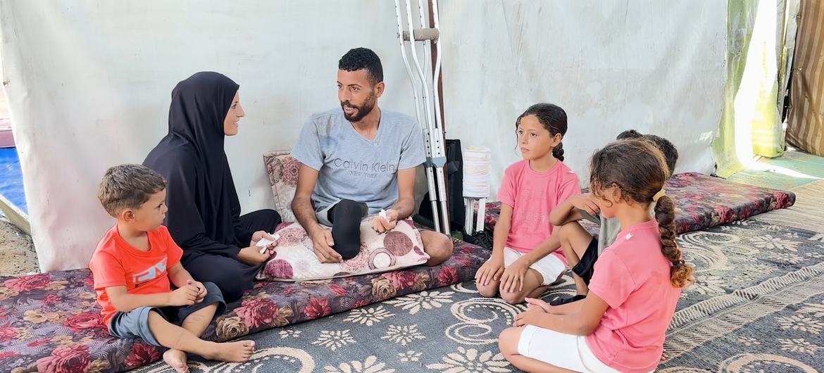 Ibrahim Abdel Nabi, un palestino desplazado en Gaza, sentado en su tienda de campaña con su esposa y sus cuatro hijos.