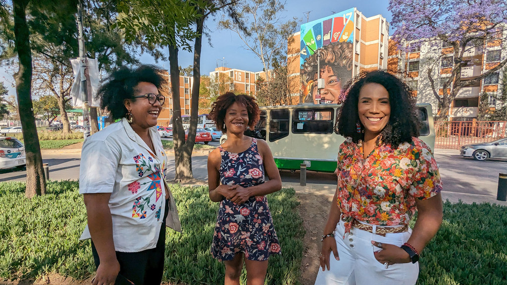 Joseline Morales, Kathleen Murrain y Gladys de León posan frente a un mural en la Alcaldía de Iztapalapa, en la Ciudad de México.