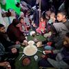 عائلة حول أطباق بسيطة وقت الإفطار في رمضان، في خيمة إيواء مؤقتة في مدينة دير البلح، وسط غزة.