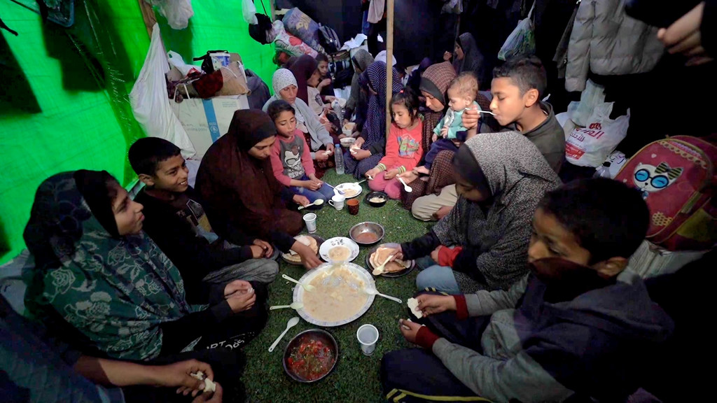 عائلة تتحلق حول أطباق بسيطة وقت الإفطار في رمضان، في خيمة إيواء مؤقتة في مدينة دير البلح، وسط غزة.