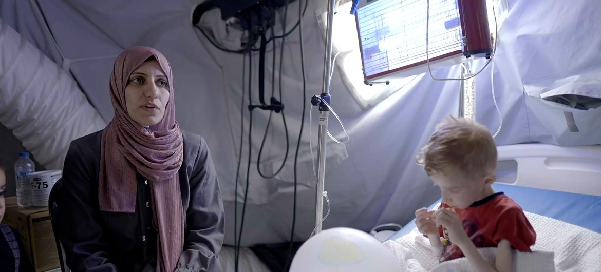 Shaima Al-Zant (izquierda) y su hijo, Fadi Al-Zant (derecha), que se encuentra entre otros niños gravemente desnutridos que reciben tratamiento en un hospital de campaña en Rafah, Gaza.