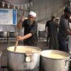 Des hommes préparent des repas chauds dans de grandes marmites sur un site de distribution alimentaire du PAM à Deir Al-Balah, dans la bande de Gaza.