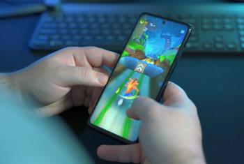 A young man plays famous mobile game Crash Bandicoot on his smartphone.