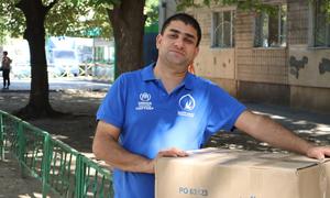 Ali carries a box of humanitarian items from the UN refugee agency, UNHCR, in Ukraine.