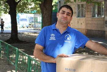 Ali carries a box of humanitarian items from the UN refugee agency, UNHCR, in Ukraine.