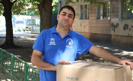 Ali carries a box of humanitarian items from the UN refugee agency, UNHCR, in Ukraine.