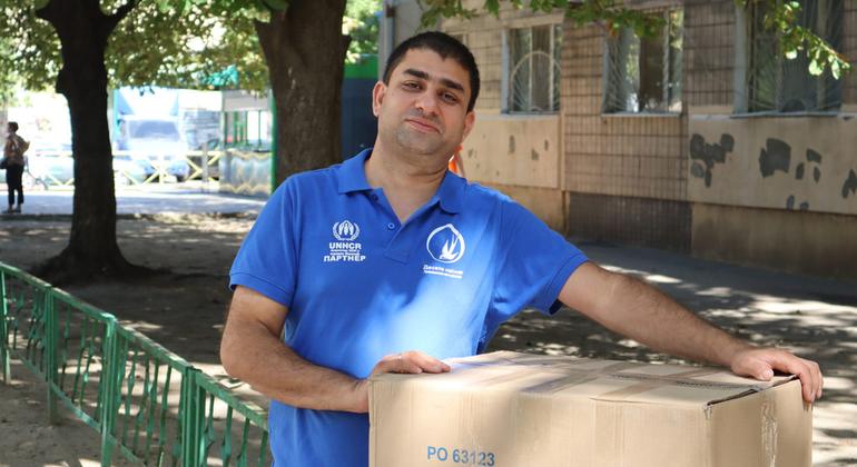 Ali porte une boîte contenant des articles humanitaires du HCR.