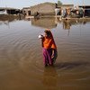 पाकिस्तान में बाढ़ के पानी से गुज़रती एक युवती.