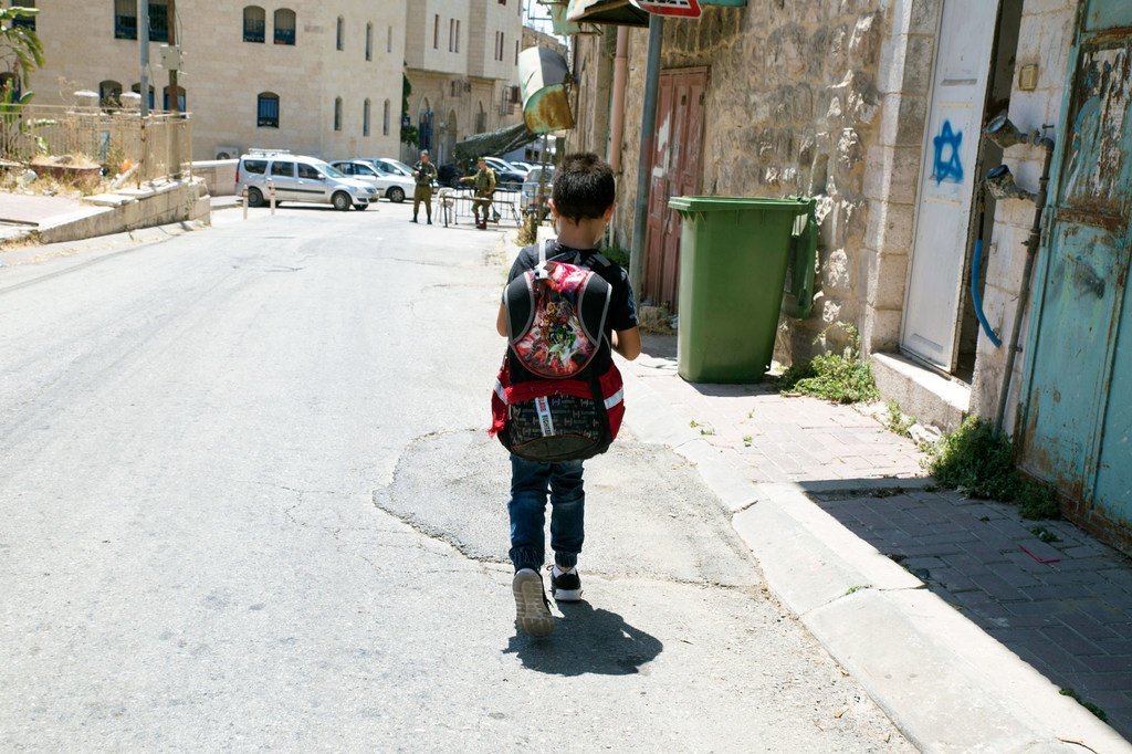 طفل يبلغ من العمر 8 سنوات يسير على طول الشارع في المدينة القديمة في الخليل باتجاه الحاجز العسكري الذي يجب أن يمر به للوصول إلى مدرسته.