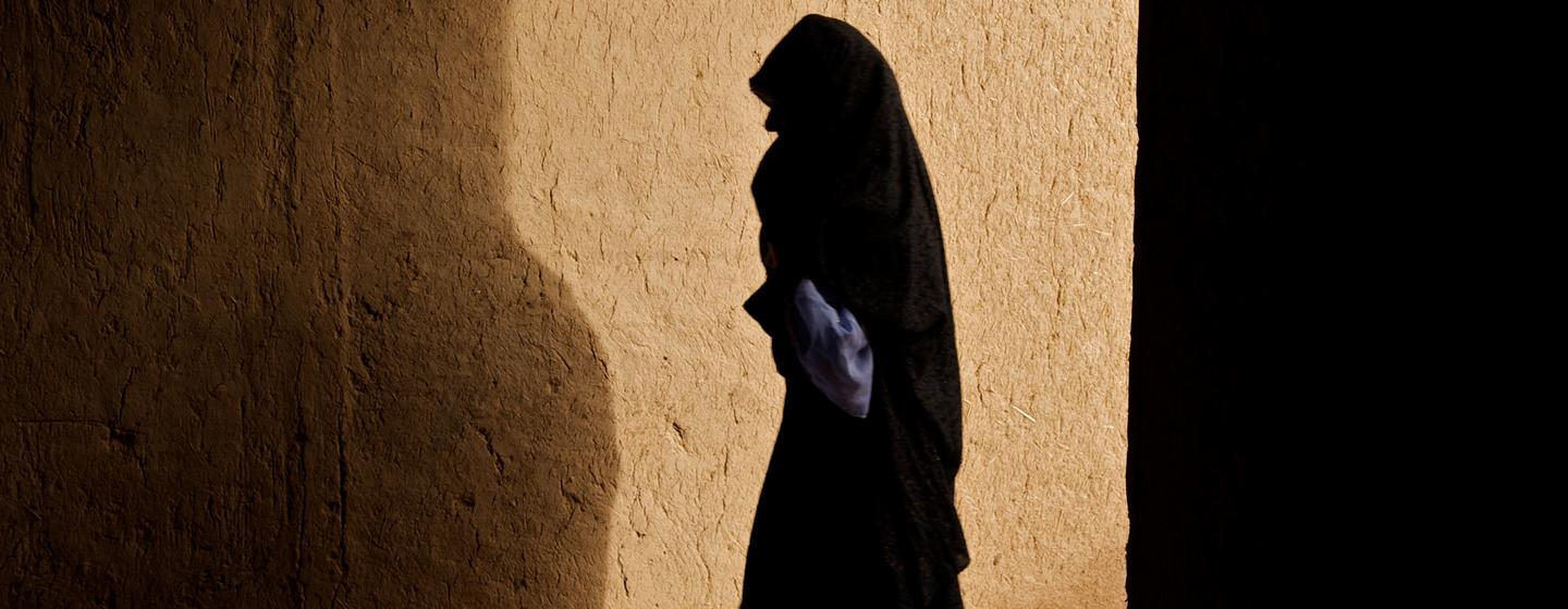 在阿富汗津达詹区的一个村庄，一名妇女正穿过一条走廊。
