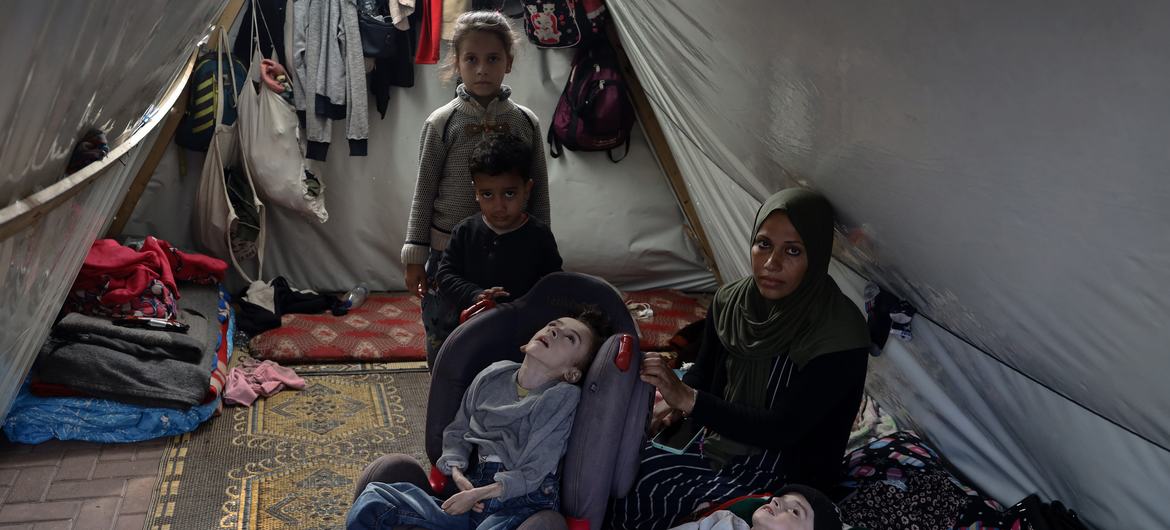 Mena, madre desplazada de cuatro hijos, con sus cuatro hijos en una tienda de campaña dentro de la Universidad Abierta Al-Quds, en la Franja de Gaza.