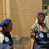 Wanawake wawili, mmoja akitabasamu na mwingine akiwa makini, wakiwa wamevaa aproni zenye nembo UN , wamesimama nje ya jengo huko Beni, DRC.
