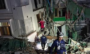 Un equipo de rescate chino intenta rescatar a una persona atrapada en el interior de un edificio de apartamentos derrumbado en Mandalay, Myanmar. 