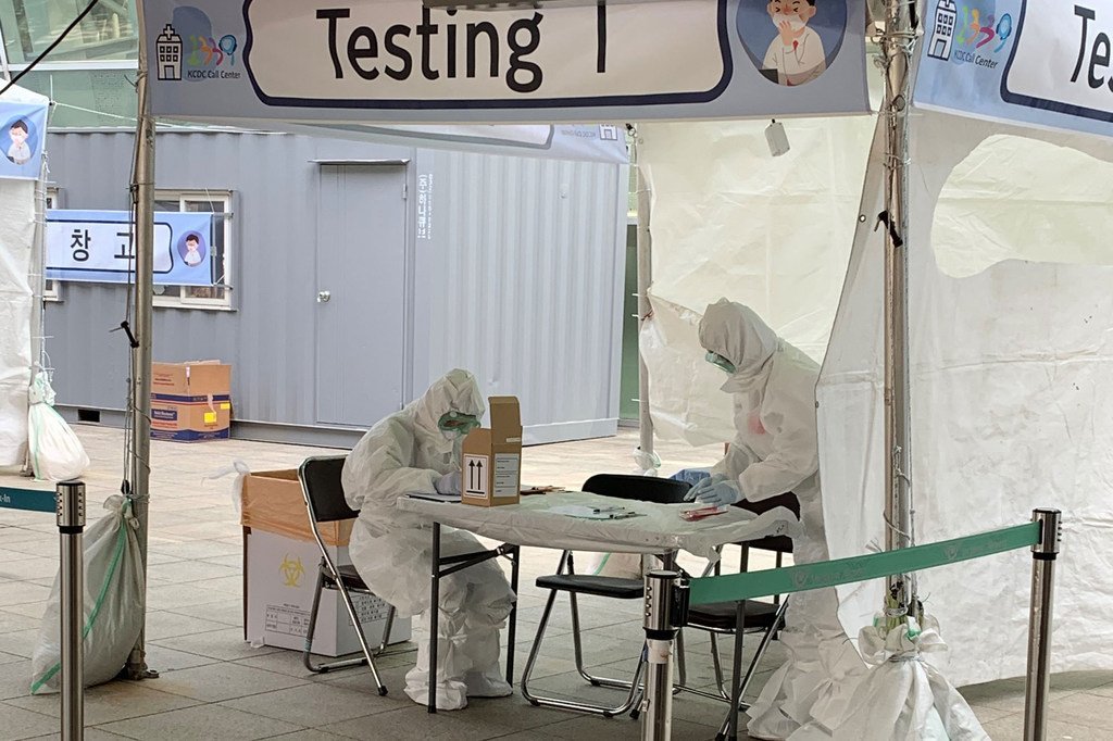 Personal sanitario con equipo de protección completo en un centro de pruebas de COVID-19 al aire libre en Corea del Sur.
