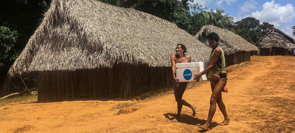 Dois homens da etnia Eñepa transportam vacinas para o ambulatório rural de San José de Kayamá, estado de Bolívar, Venezuela, em fevereiro de 2020