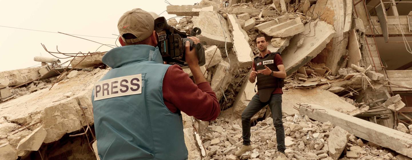 Le journaliste palestinien Mohammed Abu Namous se tient au milieu des décombres pendant qu'un caméraman le filme lors de la couverture de la guerre à Gaza.