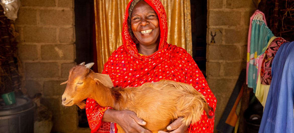Zara Bulama lleva una de las cabras que recibió de la FAO en Gongulong, Maiduguri, Nigeria, en junio de 2021.