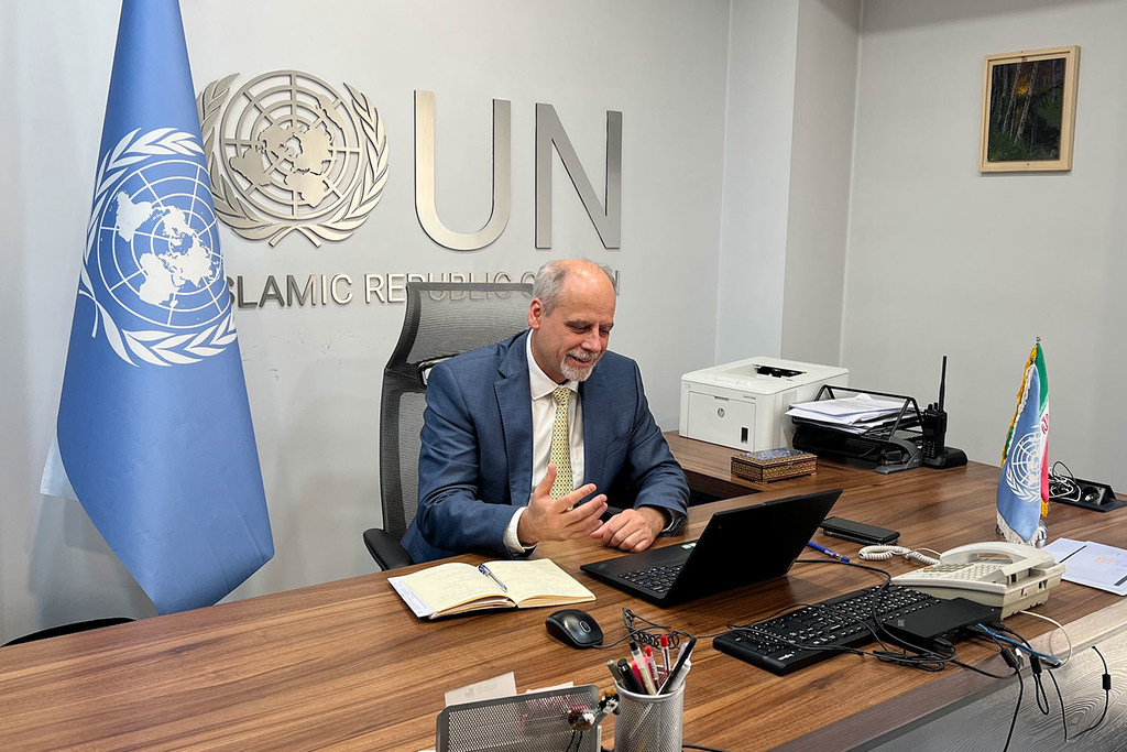 Stefan Priesner está sentado em uma mesa no escritório do Representante da ONU junto à República Islâmica do Irã, falando enquanto gesticula em direção ao seu laptop.