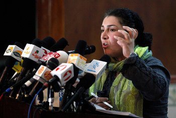 A female journalist speaks at a podium surrounded by microphones during a press conference in Kabul, Afghanistan.