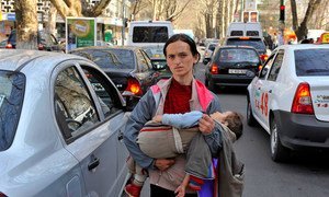 A woman carries her child while begging on the streets of Chisinau in Moldova.