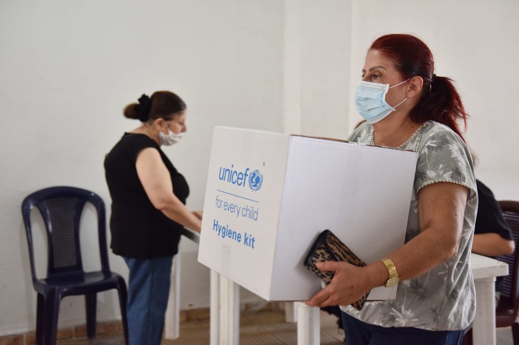 امرأة ترتدي كمامة تحمل صندوق أدوات النظافة UNICEF في برج حمود، لبنان، بعد انفجار مرفأ بيروت.