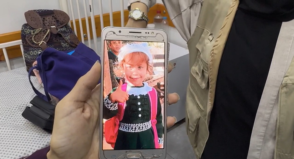 La madre de Jana muestra en su teléfono una foto de Jana antes de padecer hambruna. 