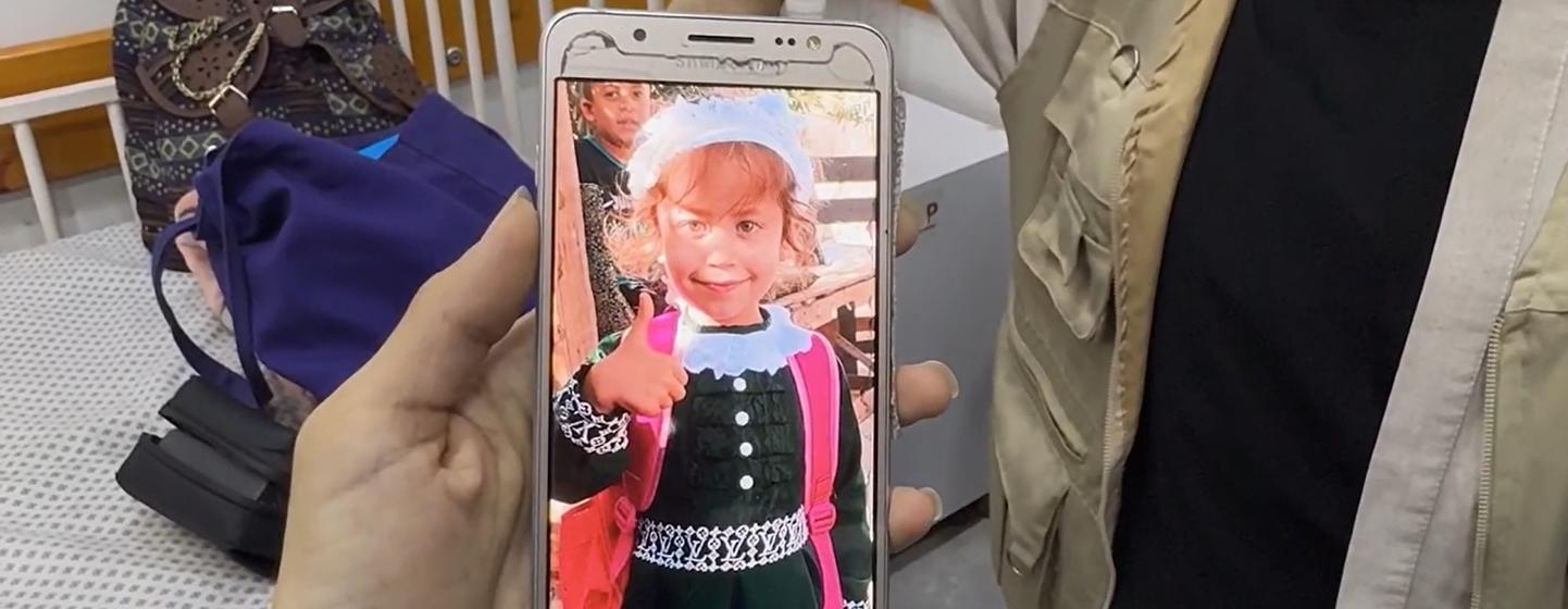 La madre de Jana muestra en su teléfono una foto de Jana antes de padecer hambruna. 