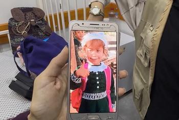 La madre de Jana muestra en su teléfono una foto de Jana antes de padecer hambruna. 