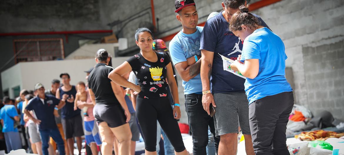 Imigrantes venezuelanos retidos na Cidade do Panamá fazem fila para distribuição de ajuda.