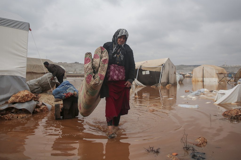 Une femme tente de sauver ses affaires après les inondations qui ont touché son camp dans le nord-ouest de la Syrie (Archives)