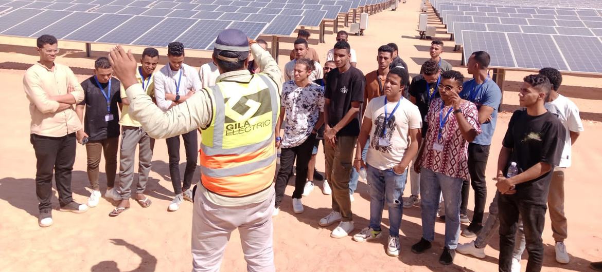 مجموعة من طلاب الجامعة في جولة في مشروع بنبان للطاقة الشمسية في أسوان بمصر، يستمعون إلى مرشد من شركة جيزة إلكتريك.