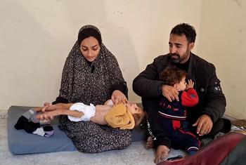 والدة الطفلة مسك المدهون، التي تعاني من سوء التغذية الحاد، تحتضنها وبجانبها زوجها وابنها.