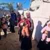 Mães e filhos esperam no posto médico do campo de Zaarab, na área de Mawasi, a oeste de Khan Younis, apoiados pelo Unicef