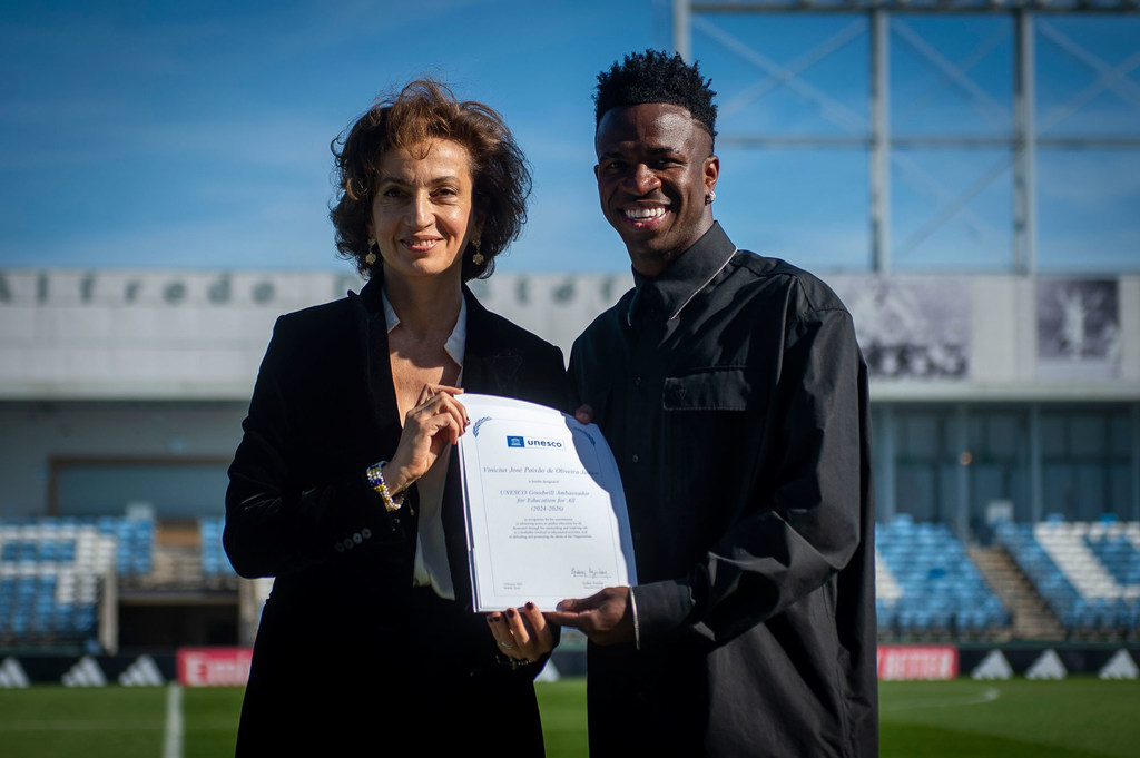 Audrey Azoulay entrega un certificado de Embajador de Buena Voluntad a Vinícius Júnior en el centro de entrenamiento del Real Madrid.