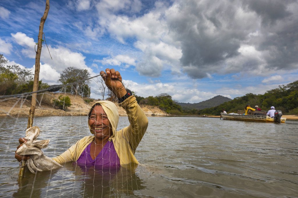 سيّدة تقوم باصطياد السمك في مياه ضحلة في أحد أنهار غيانا.