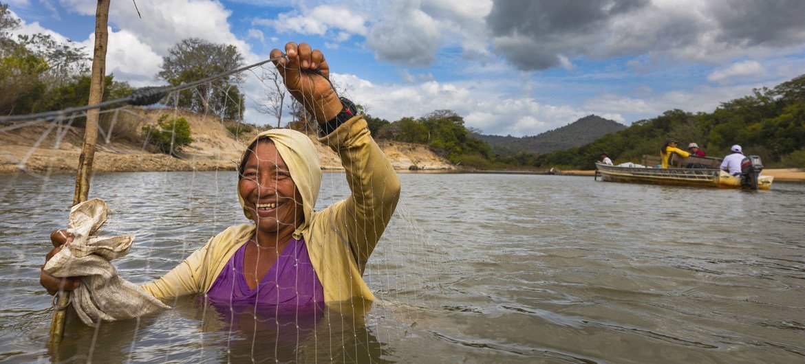 Uma mulher local usa uma rede para pescar nas águas rasas do rio Rupununi, na Guiana