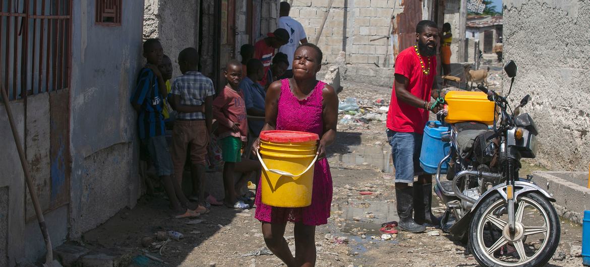 Una mujer de Puerto Príncipe (Haití) transporta agua que ha comprado a un comerciante local.