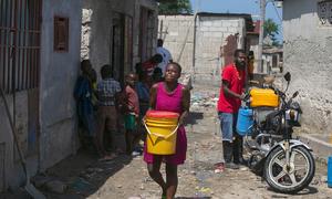 A woman in Port-au-Prince, Haiti, carries water she has bought from a local trader.