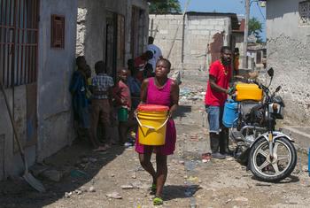 Une femme de Port-au-Prince, en Haïti, transporte de l'eau qu'elle a achetée à un commerçant local.