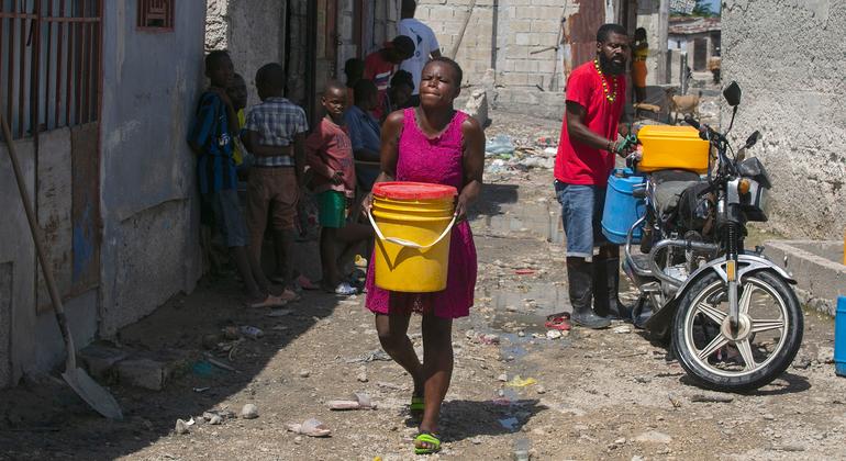 امرأة في بورت أو برنس، هايتي، تحمل المياه التي اشترتها من تاجر محلي.