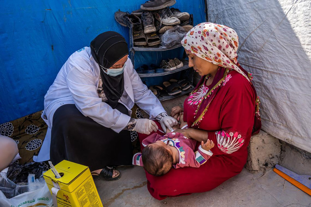 Una trabajadora de salud vacuna a un bebé de cinco meses en un campamento de desplazados en la región del Kurdistán iraquí. 