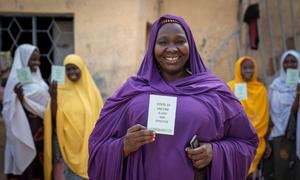 A woman shows her COVID-19 vaccine card alongside her sisters in Kano, Nigeria (file)..