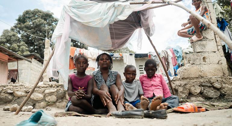 Uma mãe está sentada com os filhos num acampamento improvisado em Léogâne, nos arredores da capital do Haiti, Porto Príncipe.