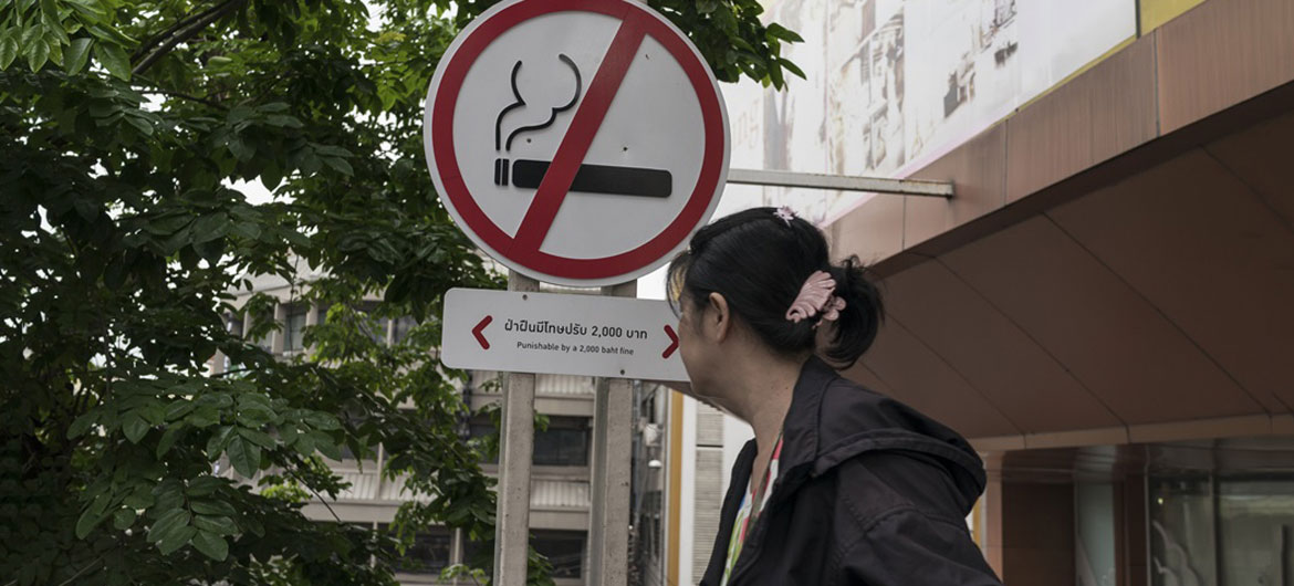 A woman walks past a no smoking sign outside a shopping centre in Bangkok, Thailand.